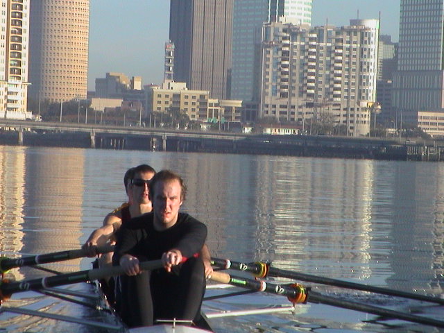 A man standing next to a body of water with buildings in the background