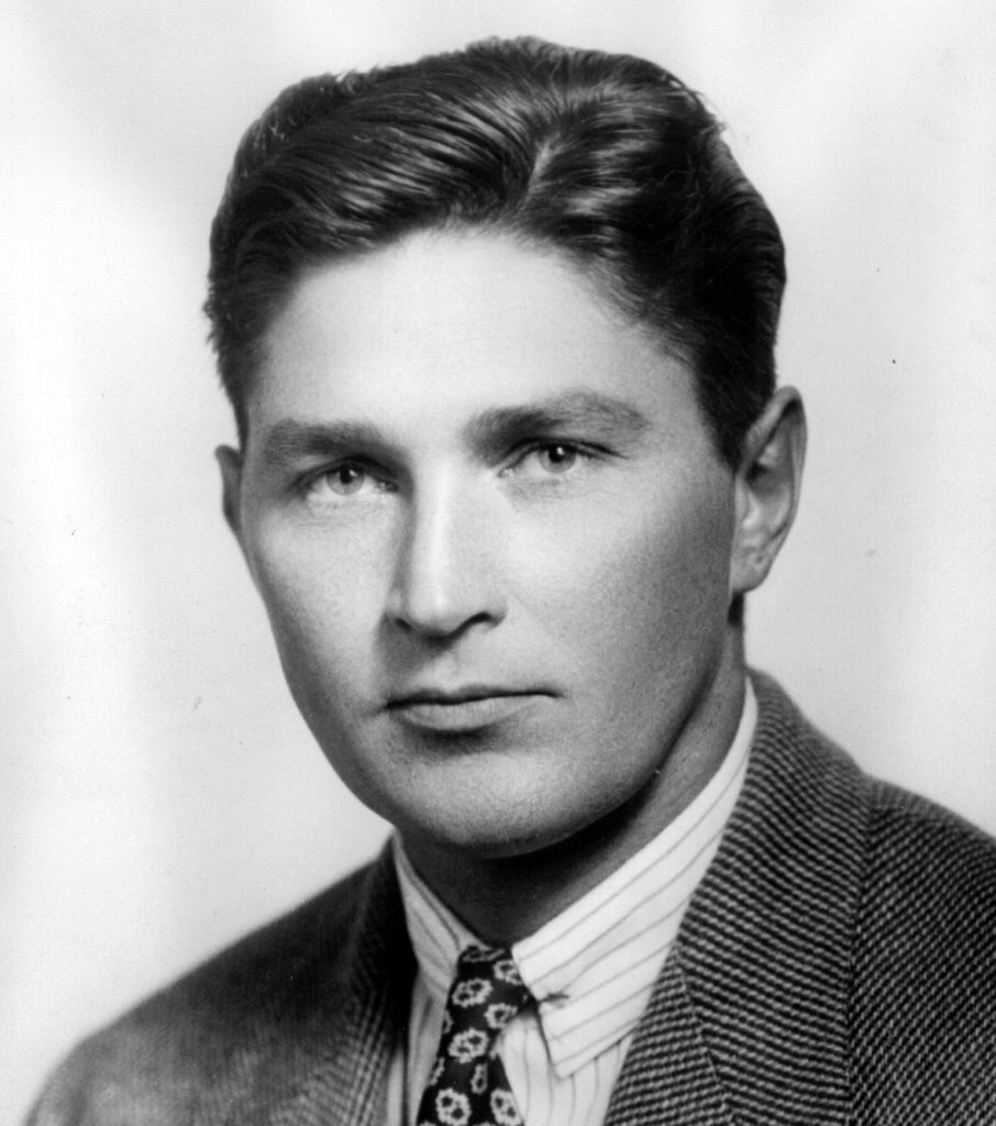A man wearing a suit and tie smiling and looking at the camera