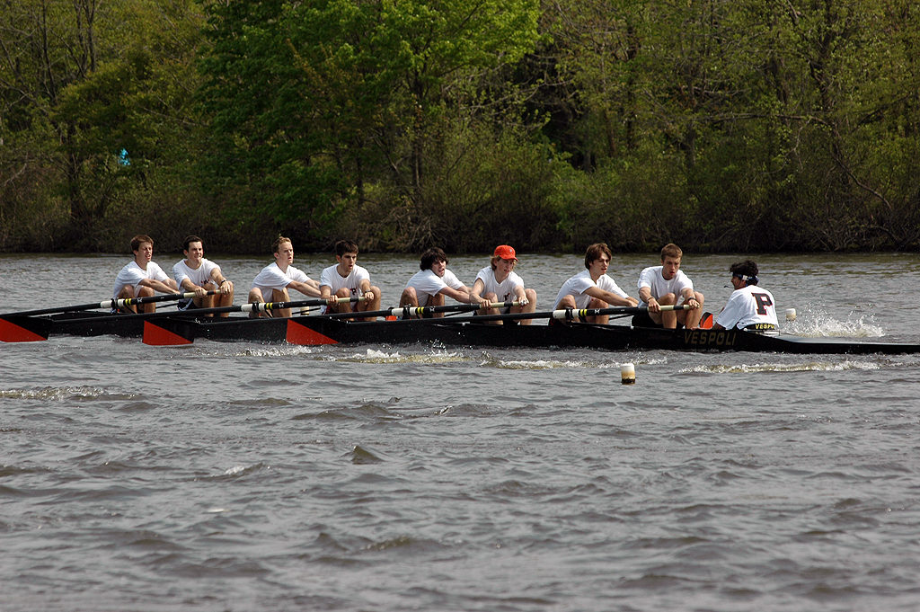 A group of people rowing a boat in a body of water