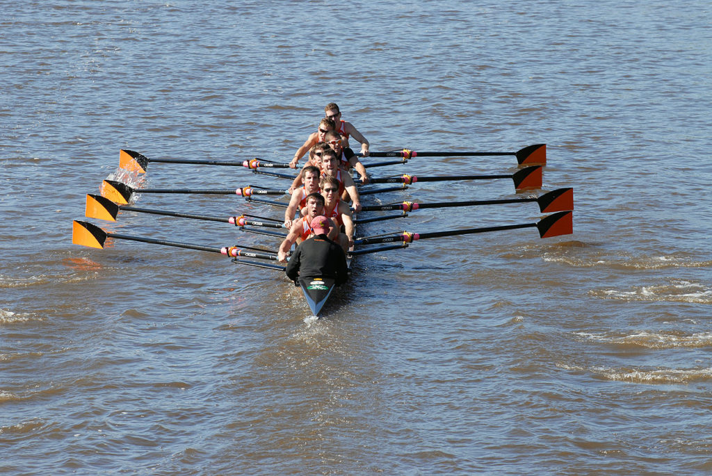 A group of people rowing a boat in a body of water