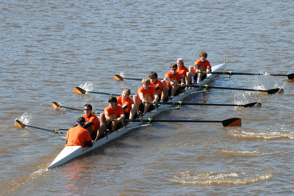 A group of people rowing a boat in a body of water