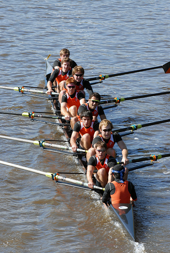 A group of people rowing a boat in a body of water