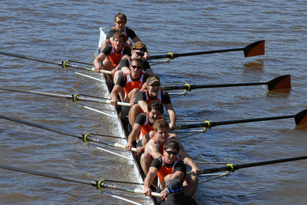 A group of people rowing a boat in a body of water