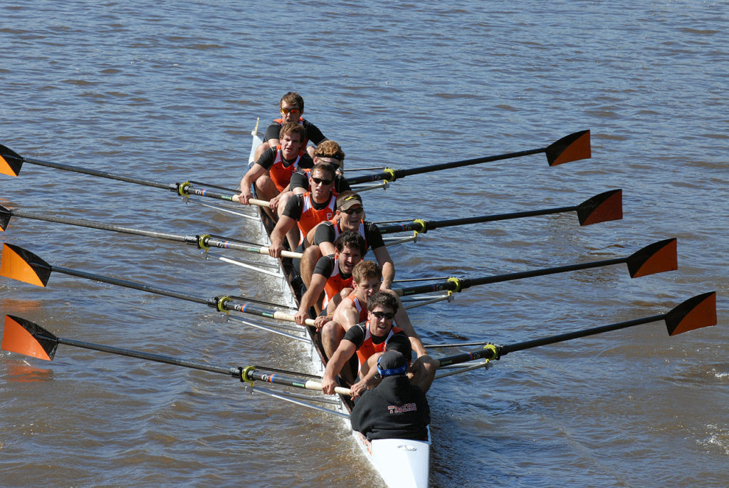 A group of people rowing a boat in a body of water