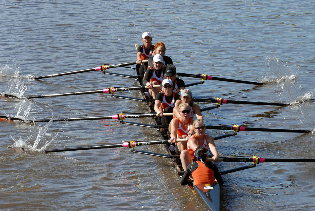 A group of people rowing a boat in a body of water