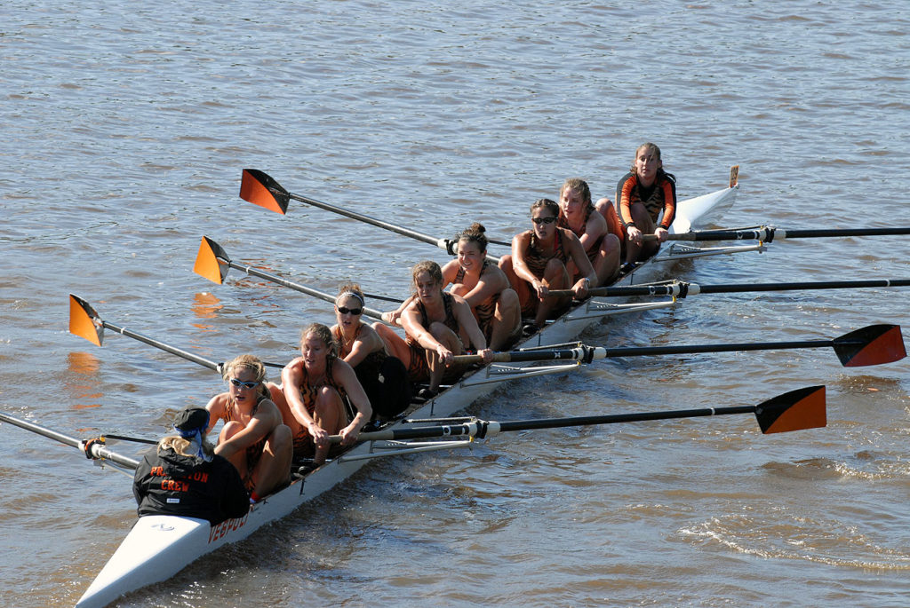 A group of people rowing a boat in a body of water