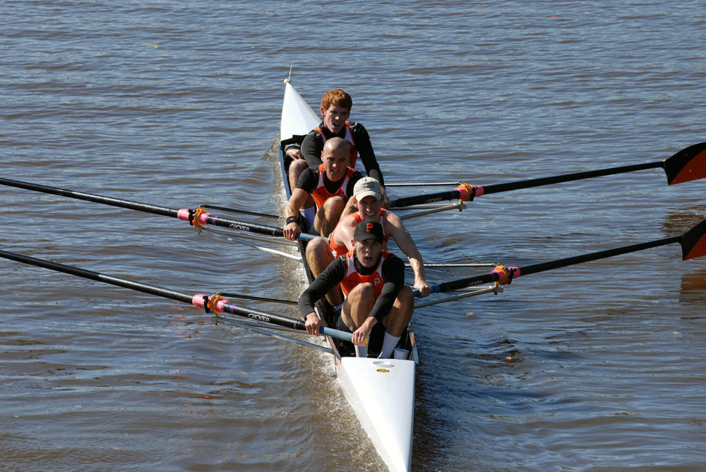 A group of people rowing a boat in a body of water