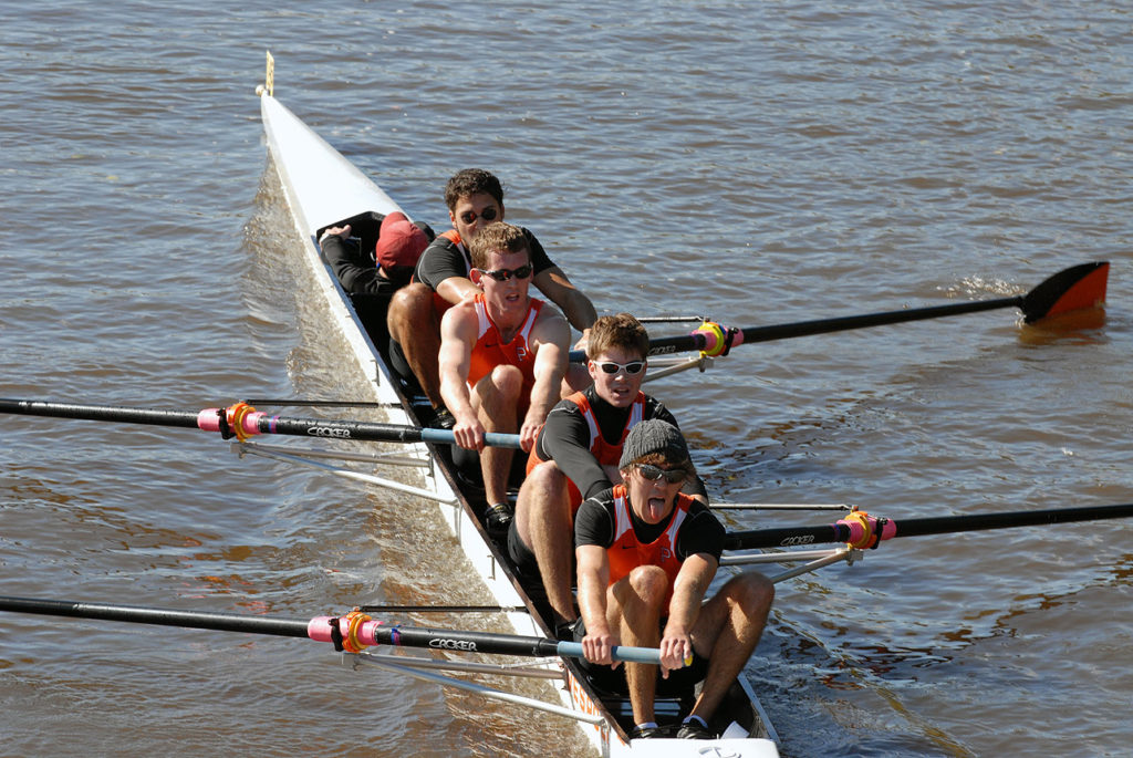 A group of people rowing a boat in a body of water