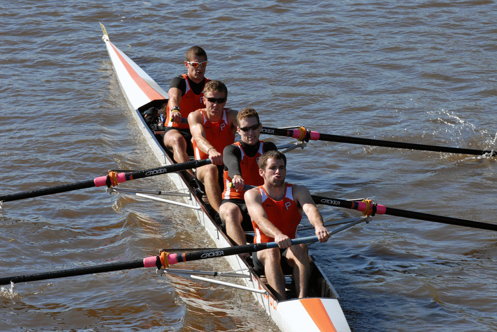 A group of people rowing a boat in a body of water