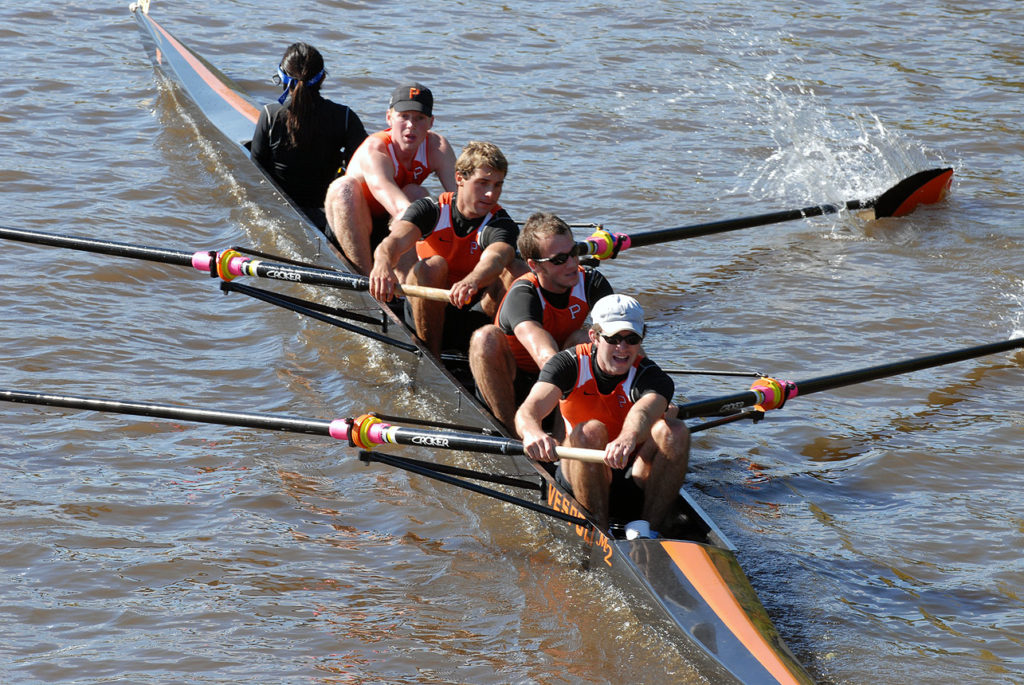 A group of people rowing a boat in a body of water