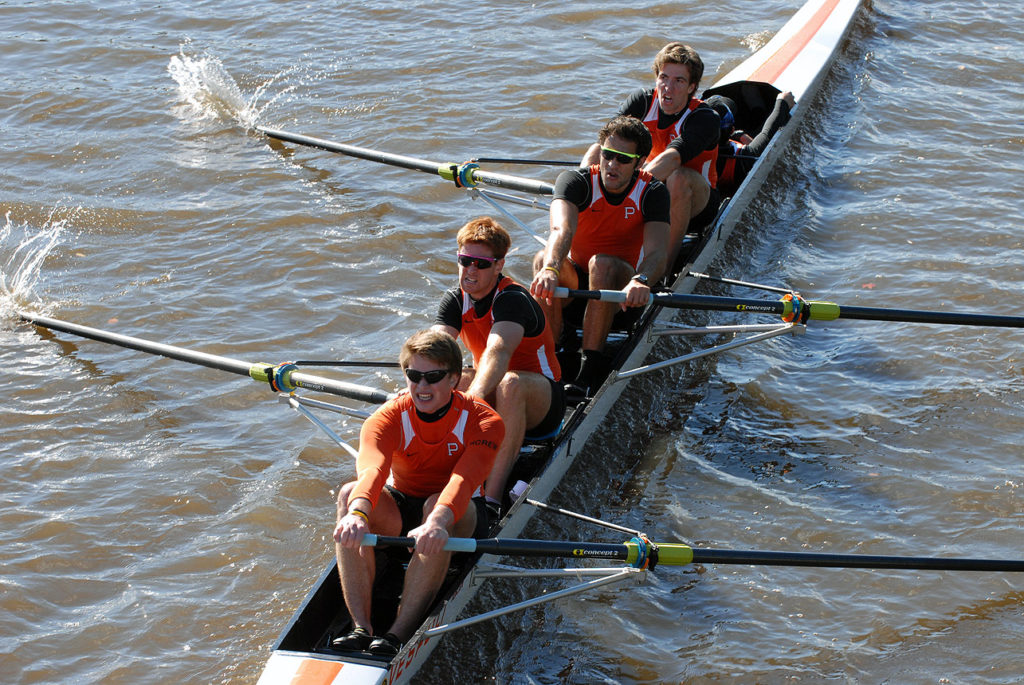 A group of people rowing a boat in a body of water