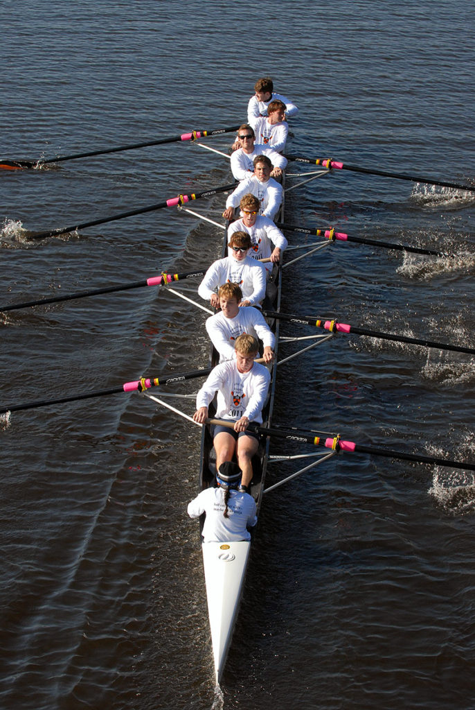 A group of people rowing a boat in a body of water