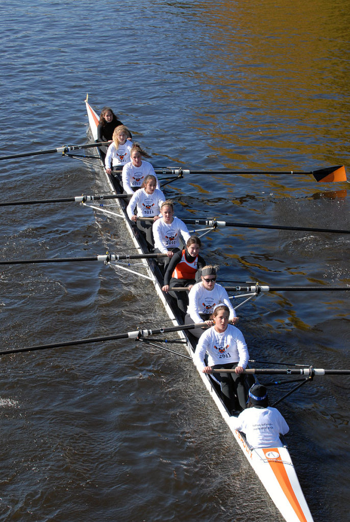 A group of people rowing a boat in a body of water