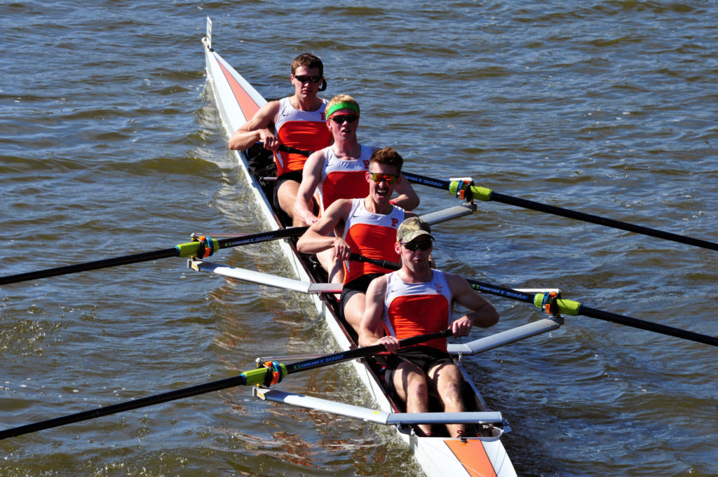 A group of people rowing a boat in a body of water