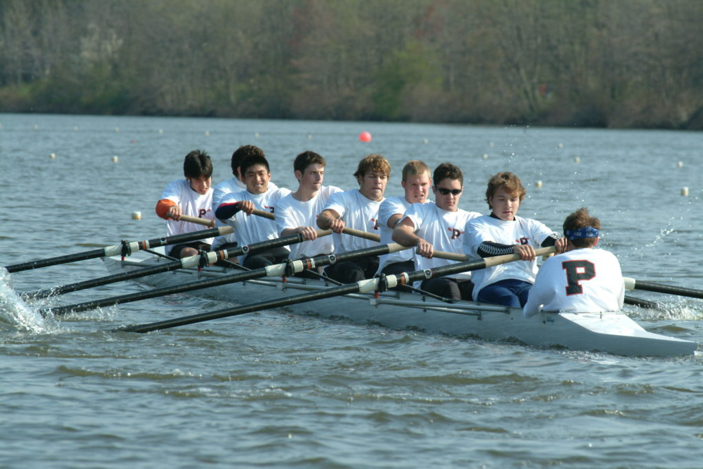 A group of people rowing a boat in a body of water