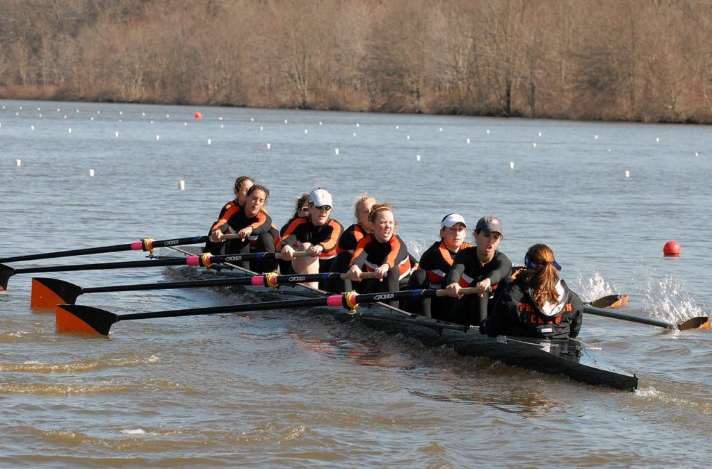 A group of people rowing a boat in a body of water