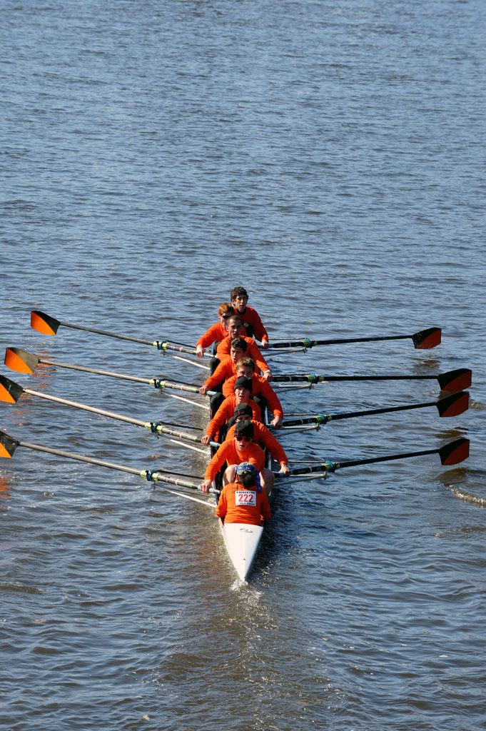 A group of people rowing a boat in a body of water