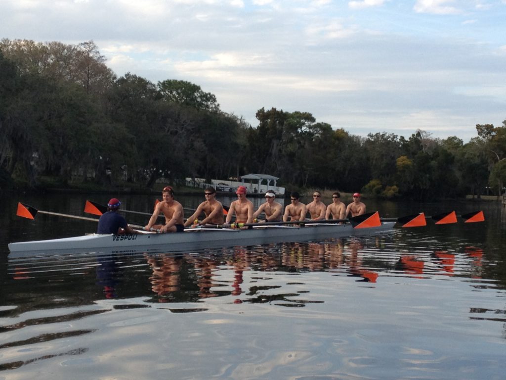 A group of people rowing a boat in a body of water