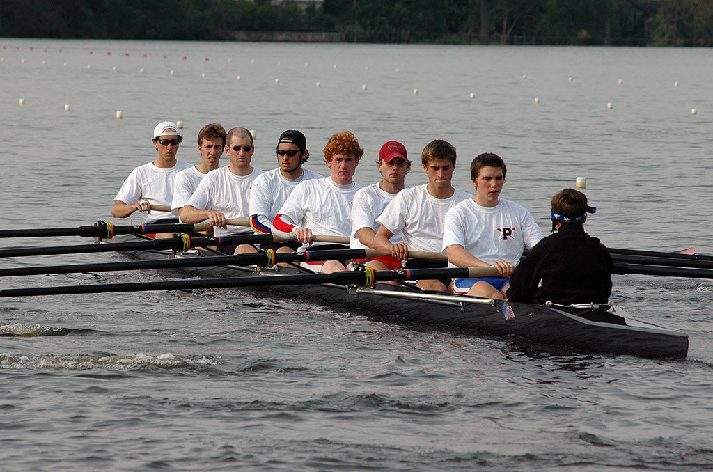 A group of people rowing a boat in a body of water