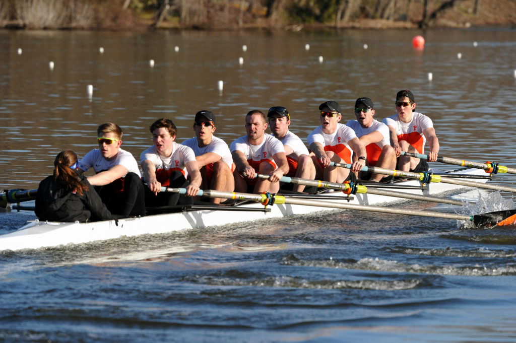 A group of people rowing a boat in a body of water