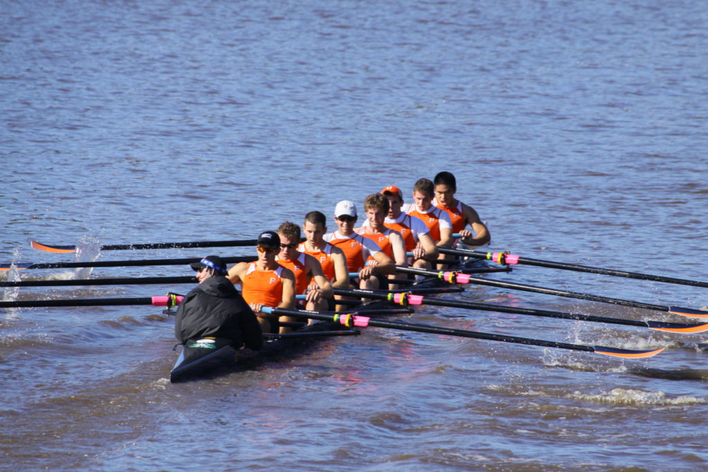 A group of people rowing a boat in a body of water