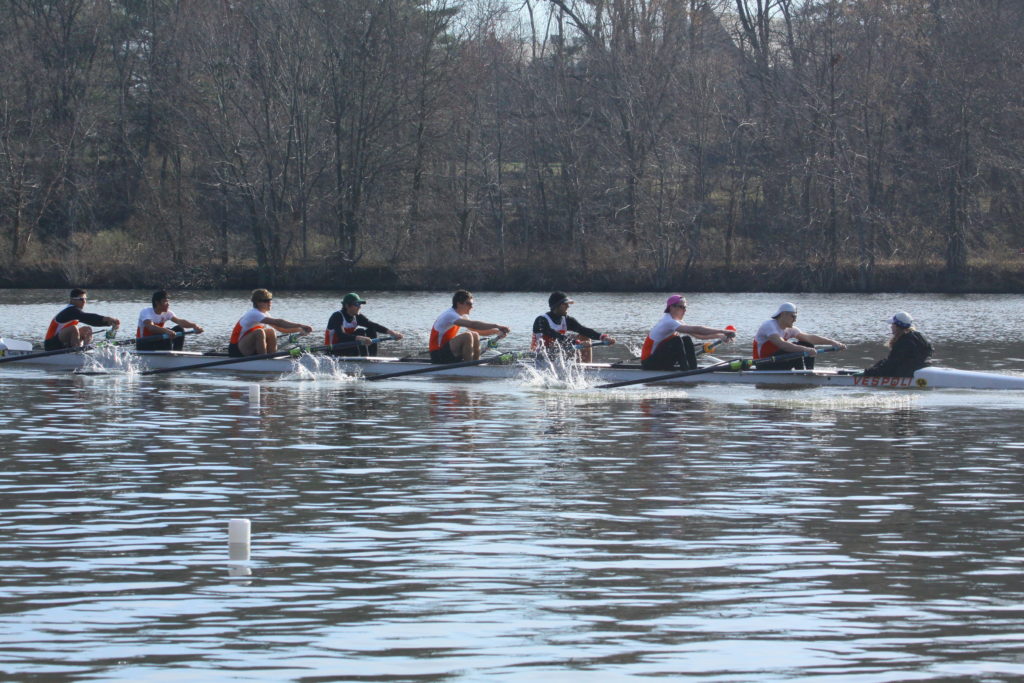 A group of people rowing a boat in a body of water