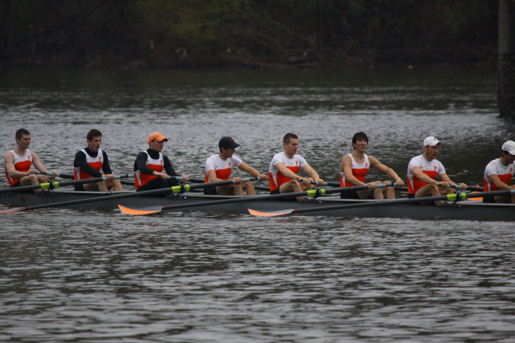 A group of people rowing a boat in a body of water