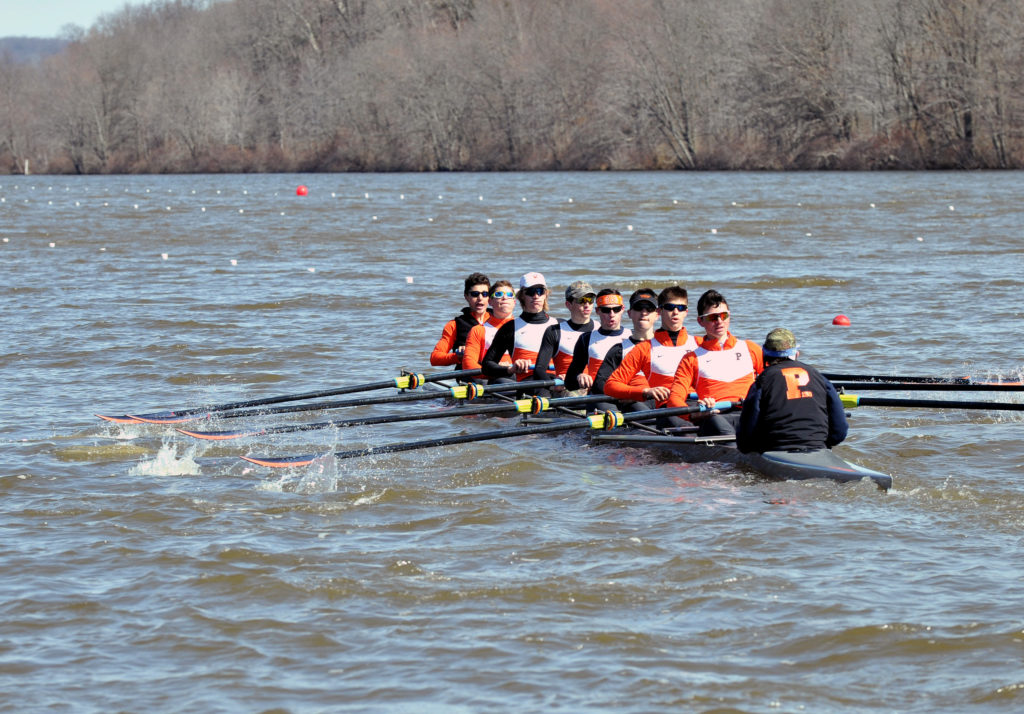 A group of people rowing a boat in a body of water