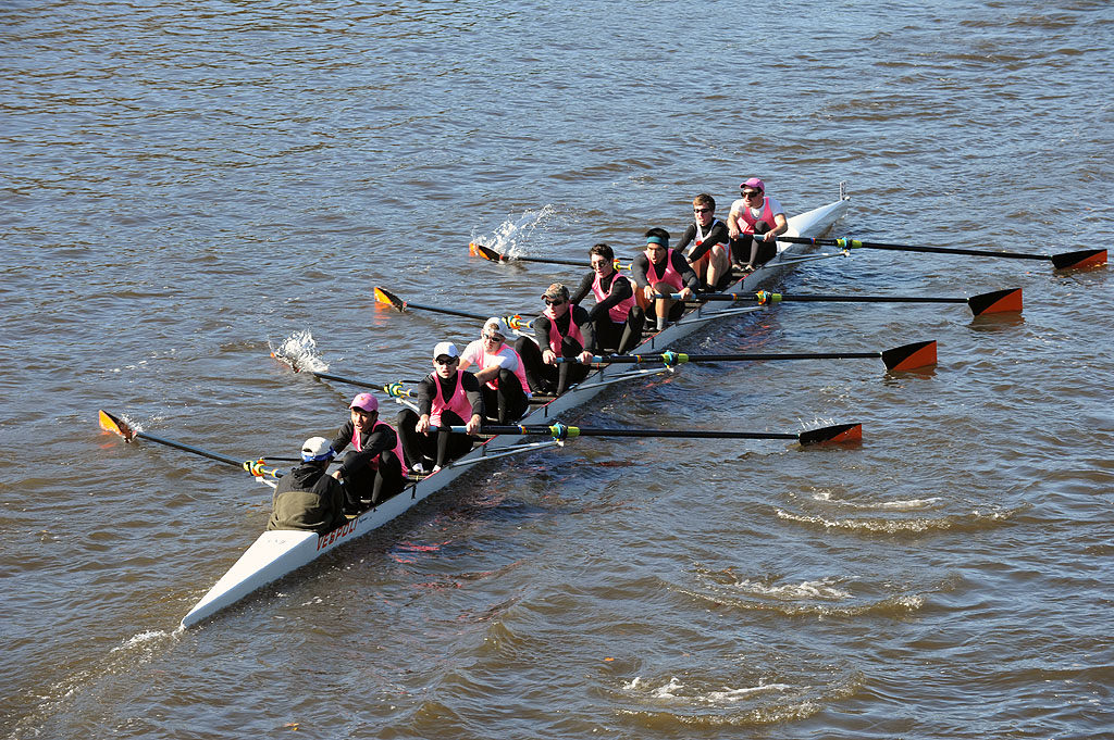 A group of people rowing a boat in a body of water