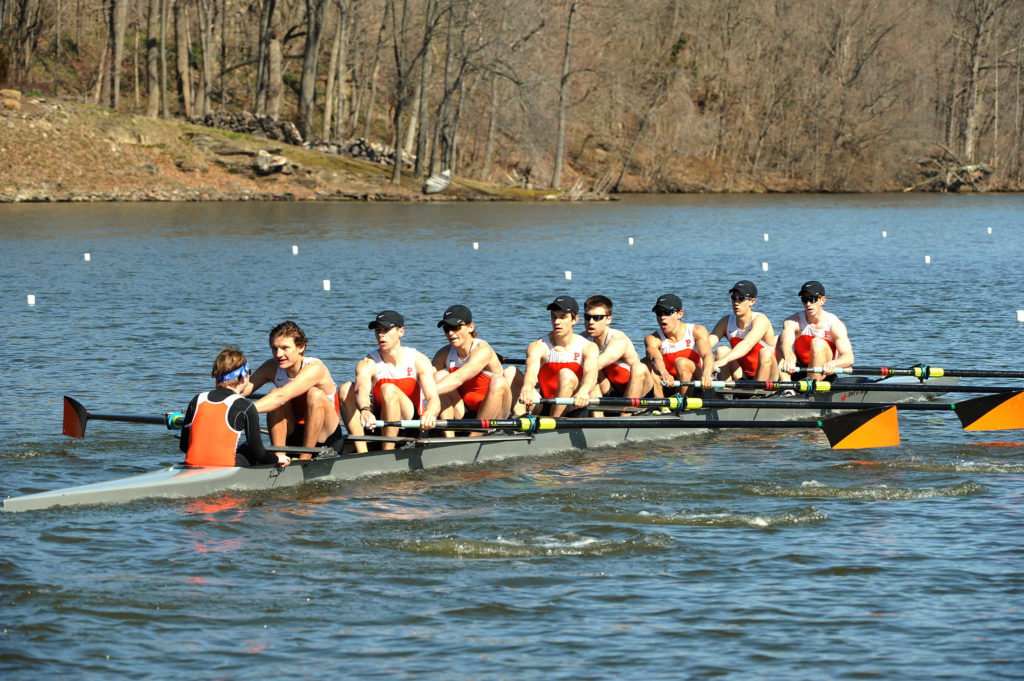 A group of people rowing a boat in a body of water