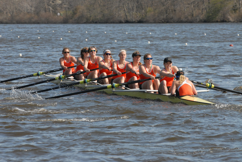 A group of people rowing a boat in a body of water