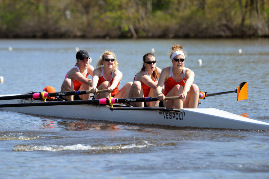 A group of people rowing a boat in a body of water