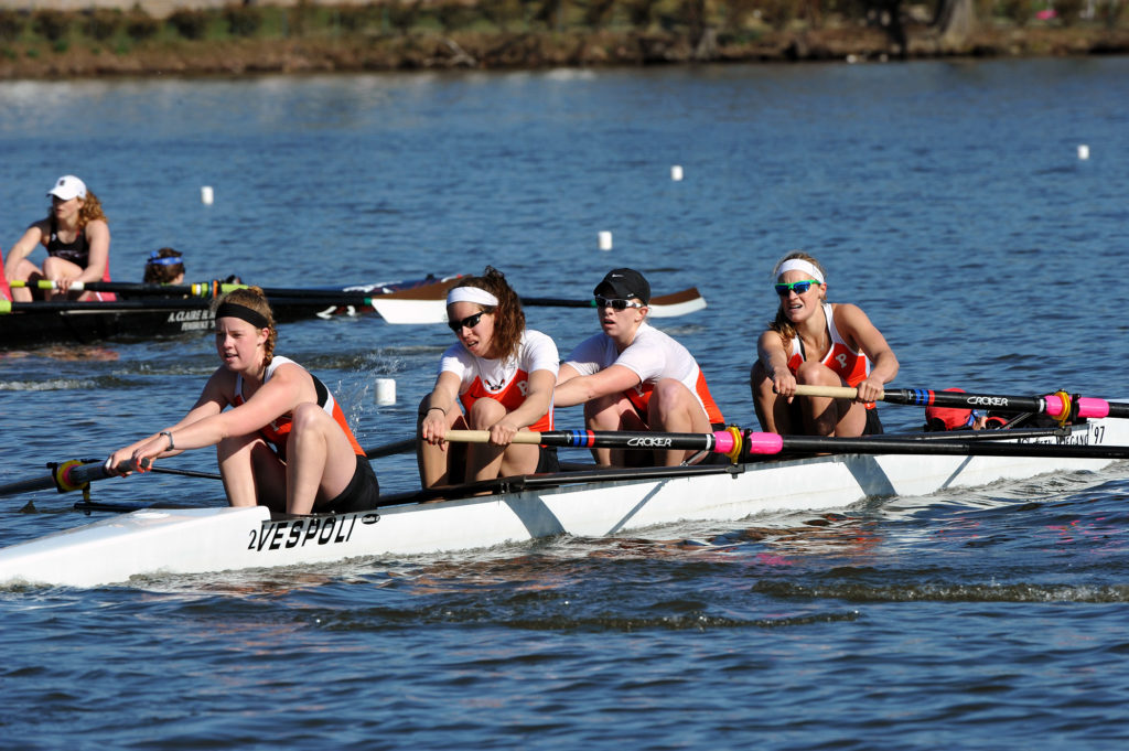 A group of people rowing a boat in a body of water