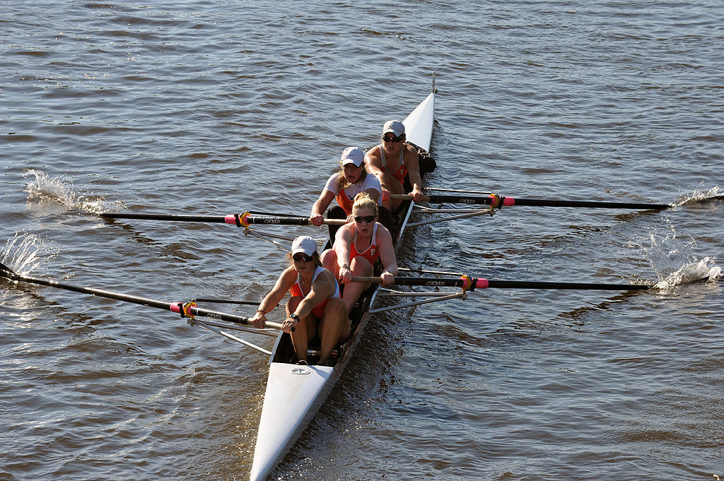 A group of people rowing a boat in a body of water