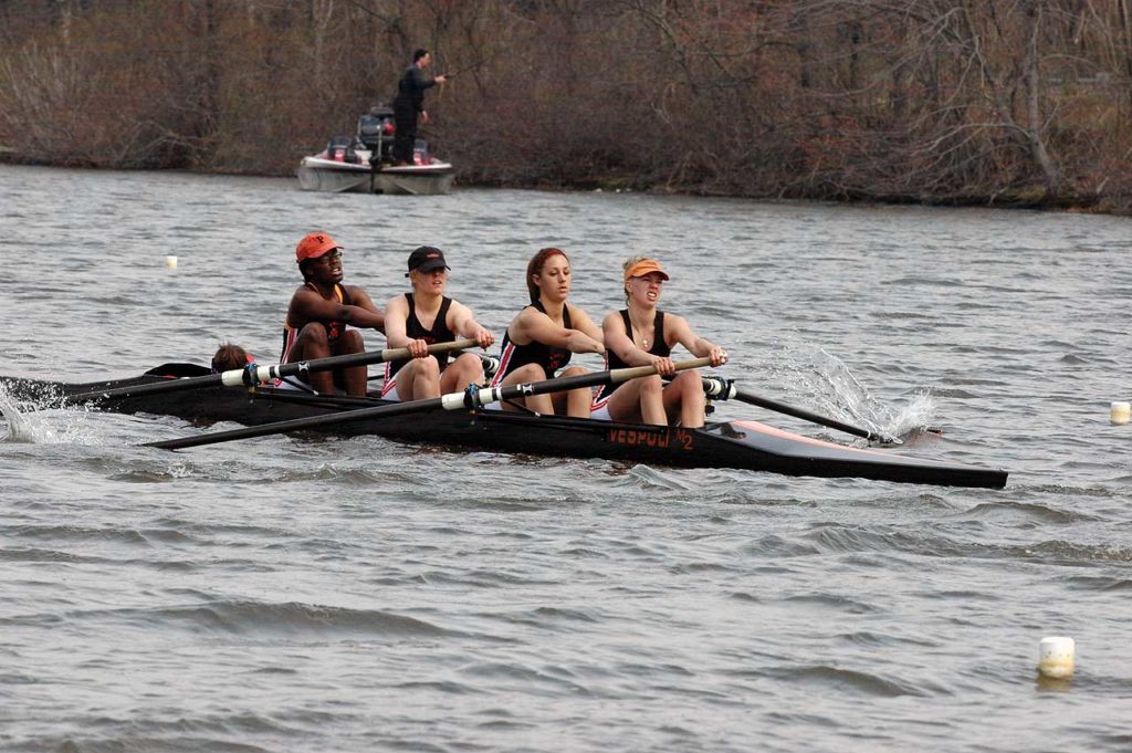 A group of people rowing a boat in a body of water