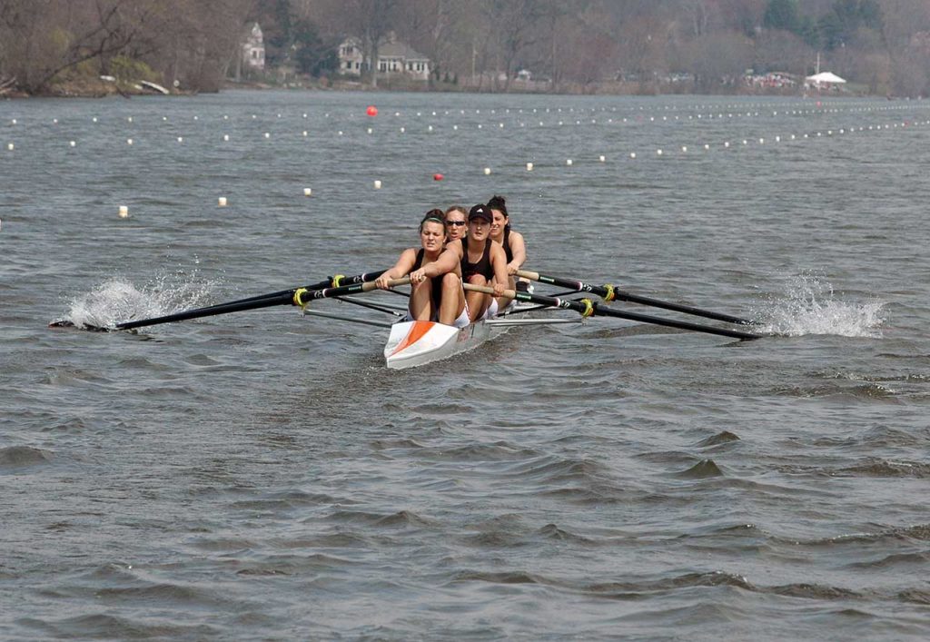 A group of people rowing a boat in a body of water