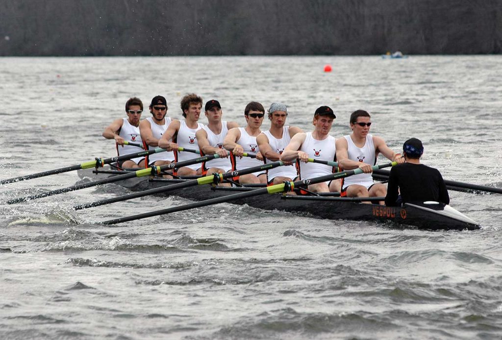 A group of people rowing a boat in a body of water