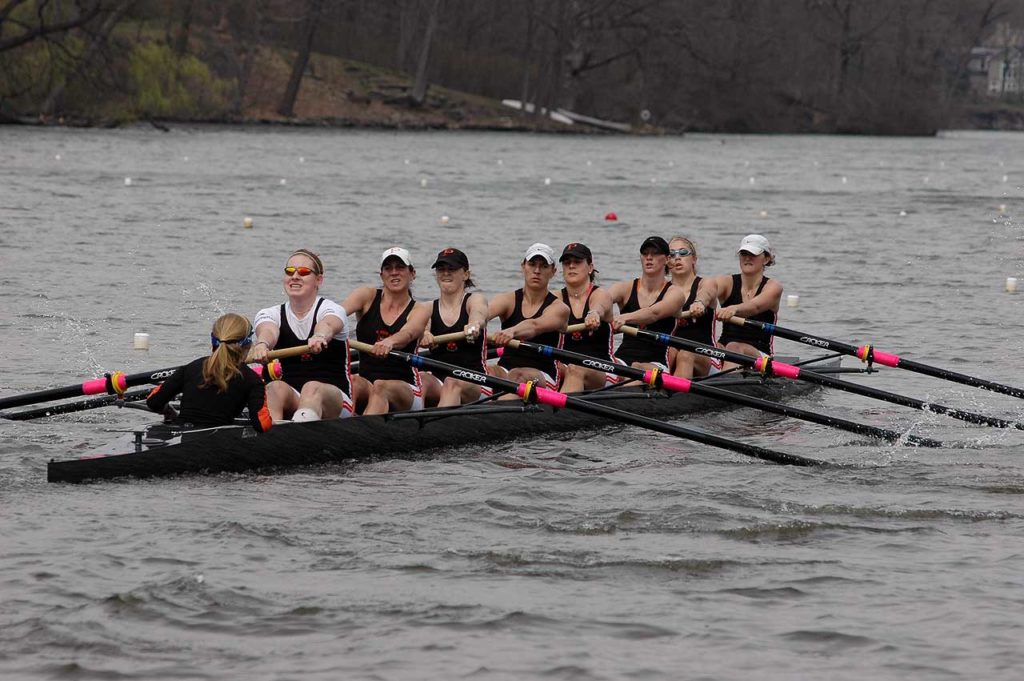 A group of people rowing a boat in a body of water