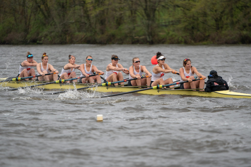 A group of people rowing a boat in a body of water